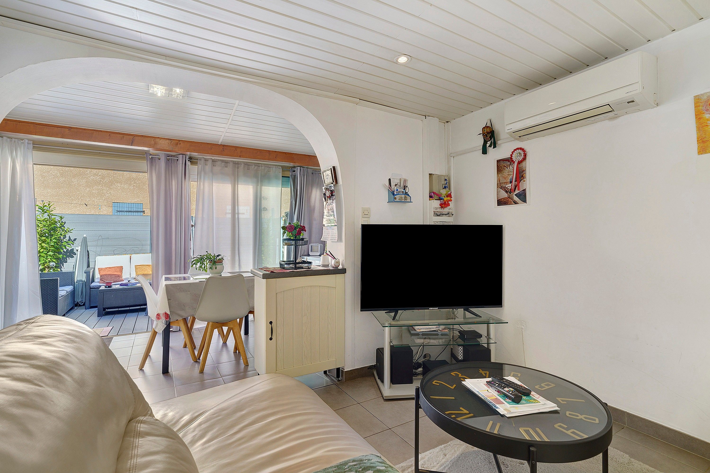 Un salon avec un canapé, un coin repas avec une table et des chaises, un téléviseur et une petite table basse.