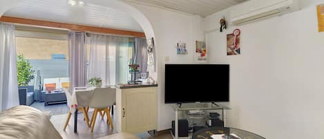 A living room with a sofa, a dining area with a table and chairs, a TV, and a small coffee table.