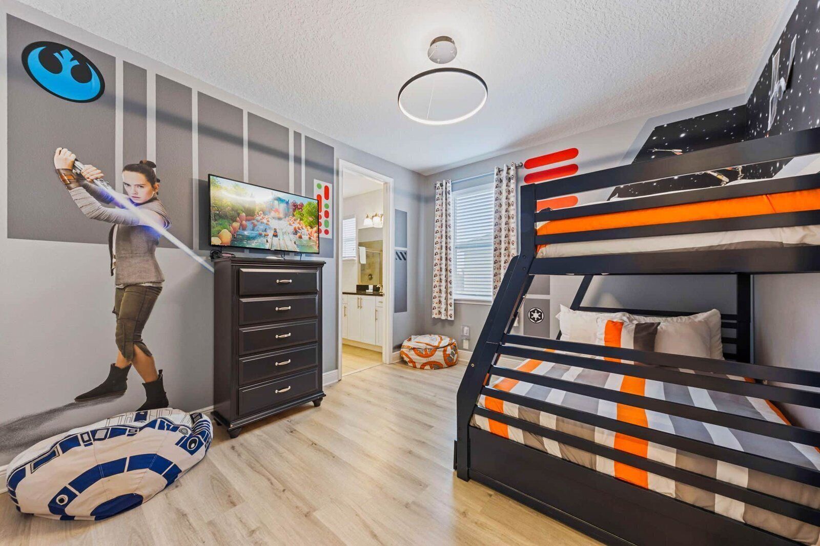 A room with a bunk bed, a dresser, a television, and a Star Wars-themed pillow.