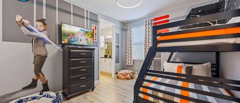 A room with a bunk bed, a dresser, a television, and a Star Wars-themed pillow.