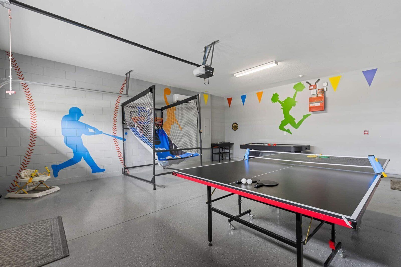 Ett bordtennisbord med nät, en projektor som är monterad i taket och en vägg med sportrelaterad dekoration.
