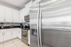 A modern kitchen with white cabinets, stainless steel appliances, and a tiled backsplash. - Harmony Palms Villa - Eight Bedroom House, Sleeps 17 (Lake Buena Vista)