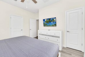 A bedroom with a bed, a dresser, a ceiling fan, and a wall-mounted TV. - Sunshine Escape - Four Bedroom House, Sleeps 8 (Kissimmee)