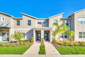 A modern building with a central entrance, a covered patio area, and a well-maintained lawn. - Amazing resort facilites, lazy river- resort pools-9 miles Disney-free wifi (Kissimmee)