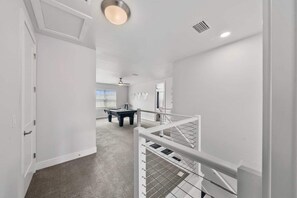 A modern interior with a pool table, a ceiling fan, and a staircase with a railing. - The Gathering Spot - Six Bedroom House, Sleeps 14 (Lake Buena Vista)