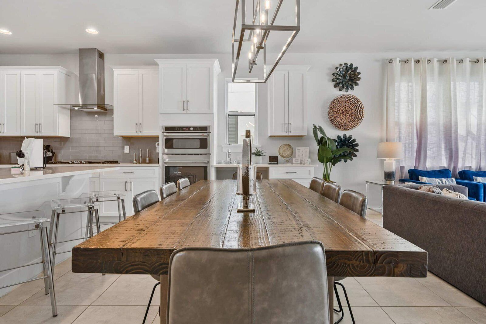 Una cocina moderna con armarios blancos, una mesa de comedor de madera y un horno empotrado.