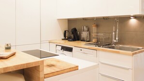 Eine moderne Küche mit weißen Schränken, einer Holz Arbeitsplatte, einem Geschirrspüler und einem Spülbecken mit Armatur.