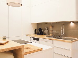 A modern kitchen with white cabinetry, a wooden countertop, a dishwasher, and a sink with a faucet. - Apartment with terrace and garden – sleeps 4 (Paris)