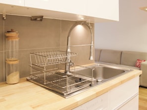 A kitchen with a stainless steel sink, a dish rack, and a wooden countertop. - Apartment with terrace and garden – sleeps 4 (Paris)
