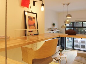 A modern living room with a wooden coffee table, a framed picture on the wall, and a view of the outdoors through large windows. - Apartment with terrace and garden – sleeps 4 (Paris)