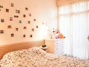 A bedroom with a bed, a dresser, a lamp, and a wall adorned with photos. - Apartment with terrace and garden – sleeps 4 (Paris)