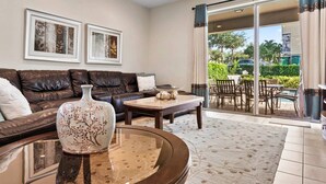 A modern living room with a leather sofa, a coffee table, and a vase. There are two framed pictures on the wall. - The Memory Box - Eight Bedroom House, Sleeps 20 (Kissimmee)