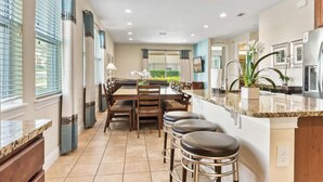A modern kitchen with a central island, bar stools, and a dining area with a view. - The Memory Box - Eight Bedroom House, Sleeps 20 (Kissimmee)