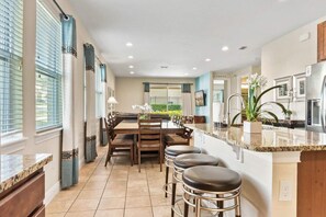 Uma cozinha moderna com uma ilha central, banquetas e uma área de jantar com vista.