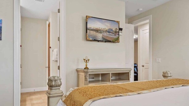 A bedroom with a bed, a nightstand, a wall-mounted TV, and a door leading to another room. - The Memory Box - Eight Bedroom House, Sleeps 20 (Kissimmee)