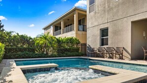 A swimming pool with a hot tub, surrounded by lounge chairs and a building with balconies. - The Memory Box - Eight Bedroom House, Sleeps 20 (Kissimmee)