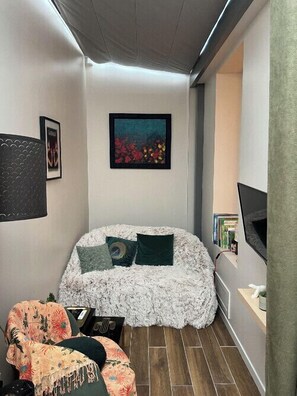 A compact room with a bed, a chair, a painting, and a television. - Charming T2 Batignolles with private courtyard (Paris)