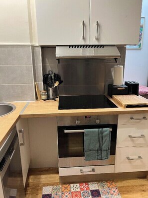 A compact kitchen with a built-in oven, a sink, and a countertop. - Charming T2 Batignolles with private courtyard (Paris)