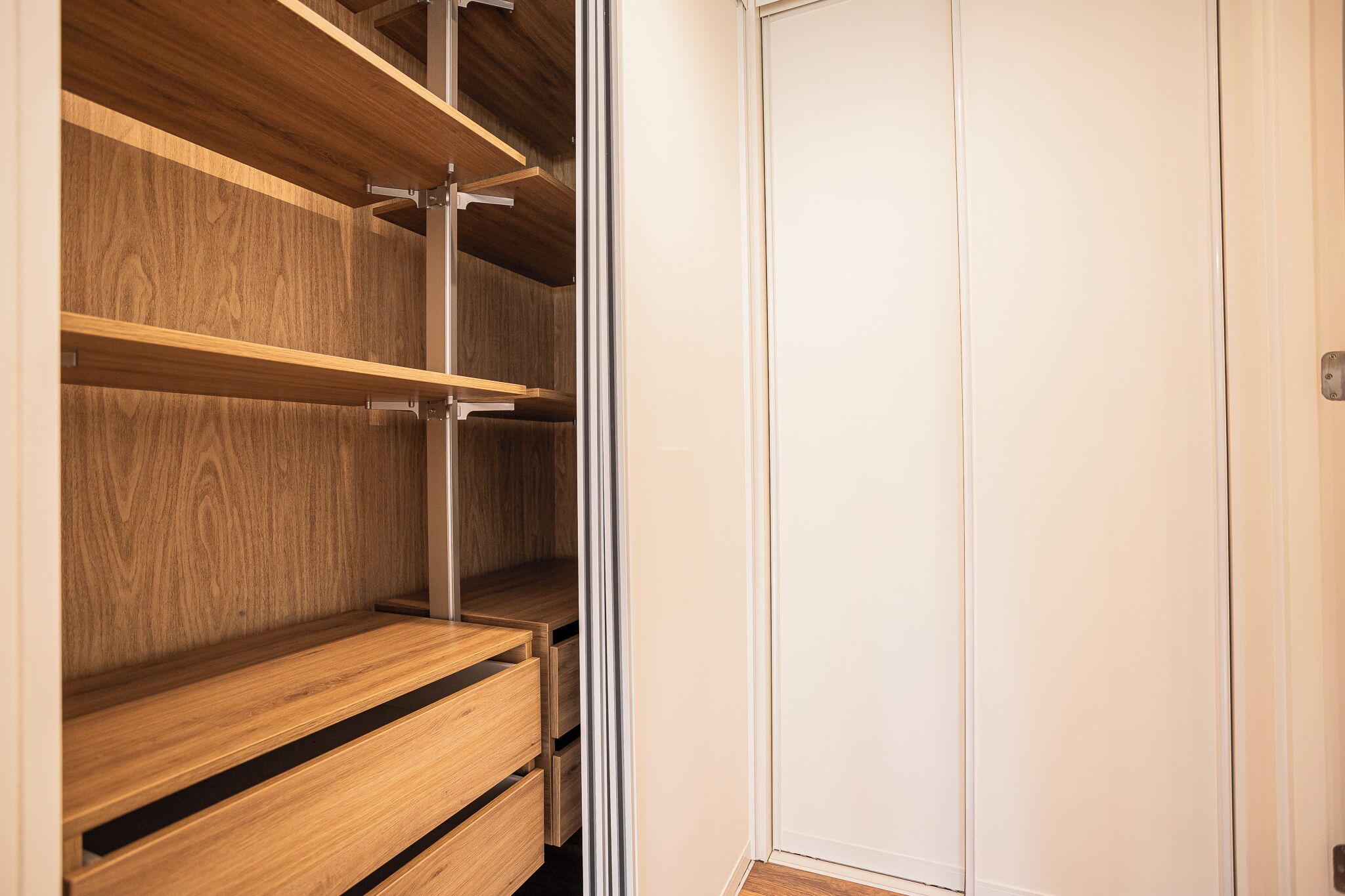 Un closet espacioso con repisas de madera y una puerta blanca.