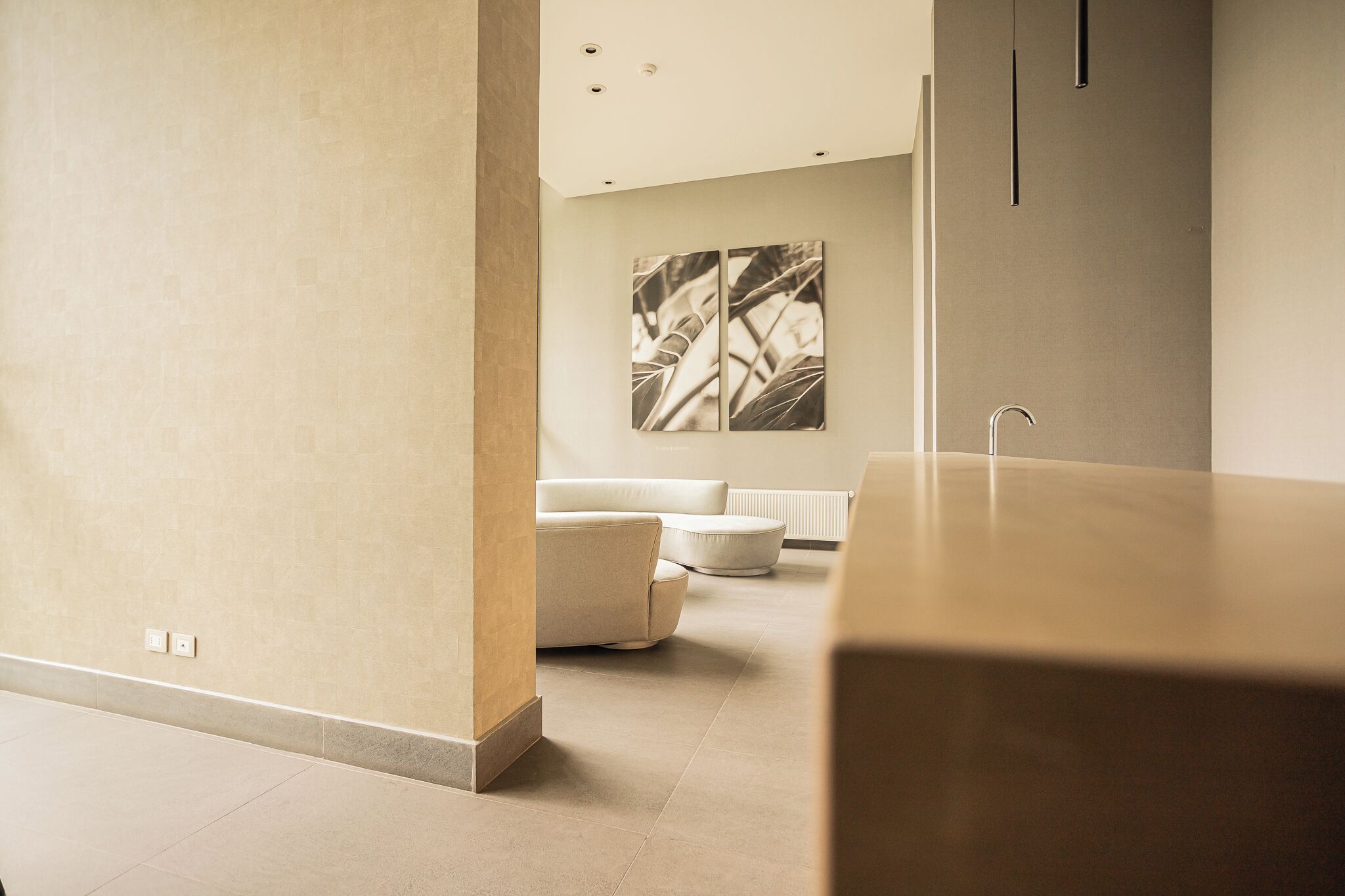 Un baño moderno con un lavamanos grande, un sofá blanco y una obra de arte colgada en la pared.