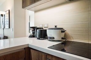 Eine Küche mit weißer Arbeitsplatte, einer schwarzen Kaffeemaschine, einem schwarz-weißen Slow Cooker und einem Toaster.