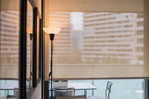 Ein Zimmer mit großem Fenster, einem Tisch und zwei Stehlampen.