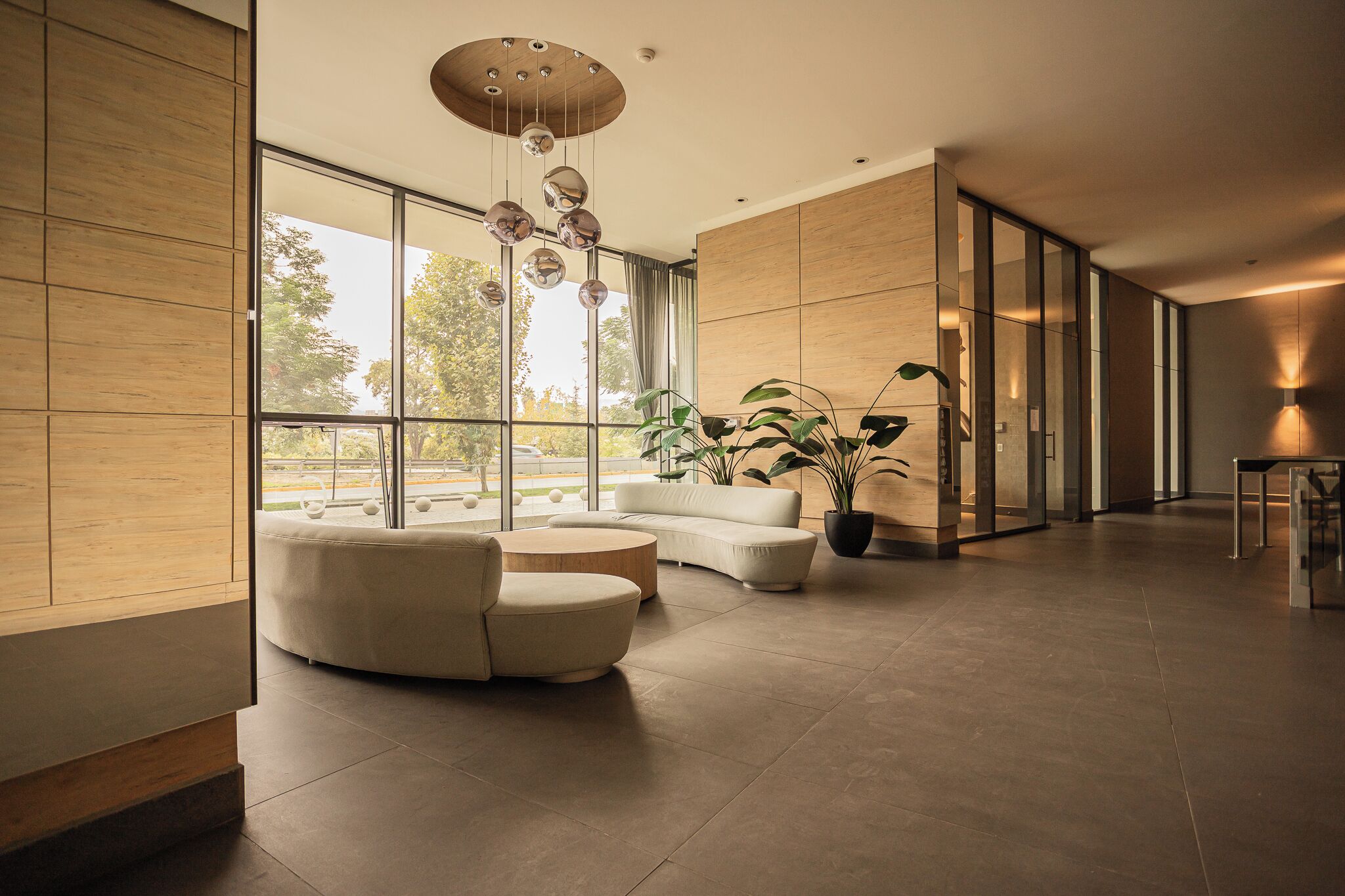A spacious, modern interior with a large window, a seating area with a sofa and armchairs, and a potted plant.
