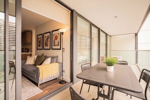 A modern living space with a sofa, a dining table, and a potted plant. - Manquehue Norte Apartments by Andes STR (Las Condes)