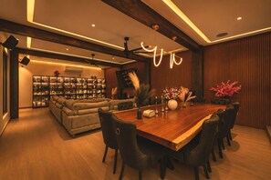 A modern living room with a wooden dining table, black leather chairs, and a bookshelf. - Villa Soho, your own boutique hotel in Cabo (Cabo San Lucas)