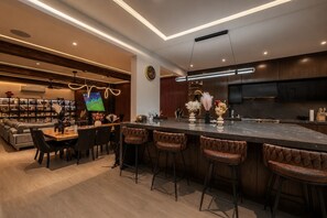 A modern kitchen with a large island, bar stools, and a dining area with a sofa and chairs. - Villa Soho, your own boutique hotel in Cabo (Cabo San Lucas)