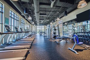 Un gimnasio con cintas de correr, máquinas de pesas y mancuernas.