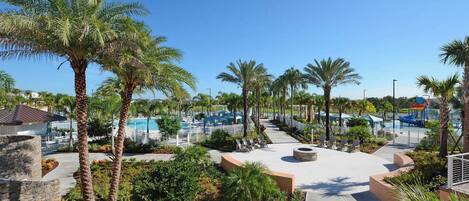 A resort with a pool area, palm trees, and a stone building.