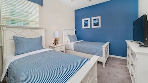 A bedroom with two beds, a nightstand, a lamp, a dresser, and a television. - Solara Resort/Private Pool and Spa/Surfing Florider/Games Room/7 miles Disney (Kissimmee)