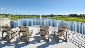 Ein Poolbereich mit Adirondack-Stühlen und Blick auf einen See.
