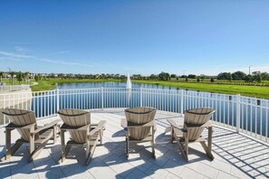 Ein Poolbereich mit Adirondack-Stühlen und Blick auf einen See.