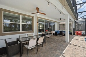 Un patio exterior con una mesa de vidrio, sillas y un sofá.