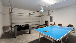 Ein Raum mit Kicker, Tischtennisplatte und einem an der Decke befestigten Projektor.