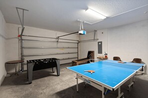 Ein Raum mit Kicker, Tischtennisplatte und einem an der Decke befestigten Projektor.
