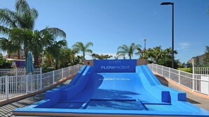 Eine blaue Wasserrutsche im Solara Resort, mit einem Zaun und Palmen im Hintergrund.
