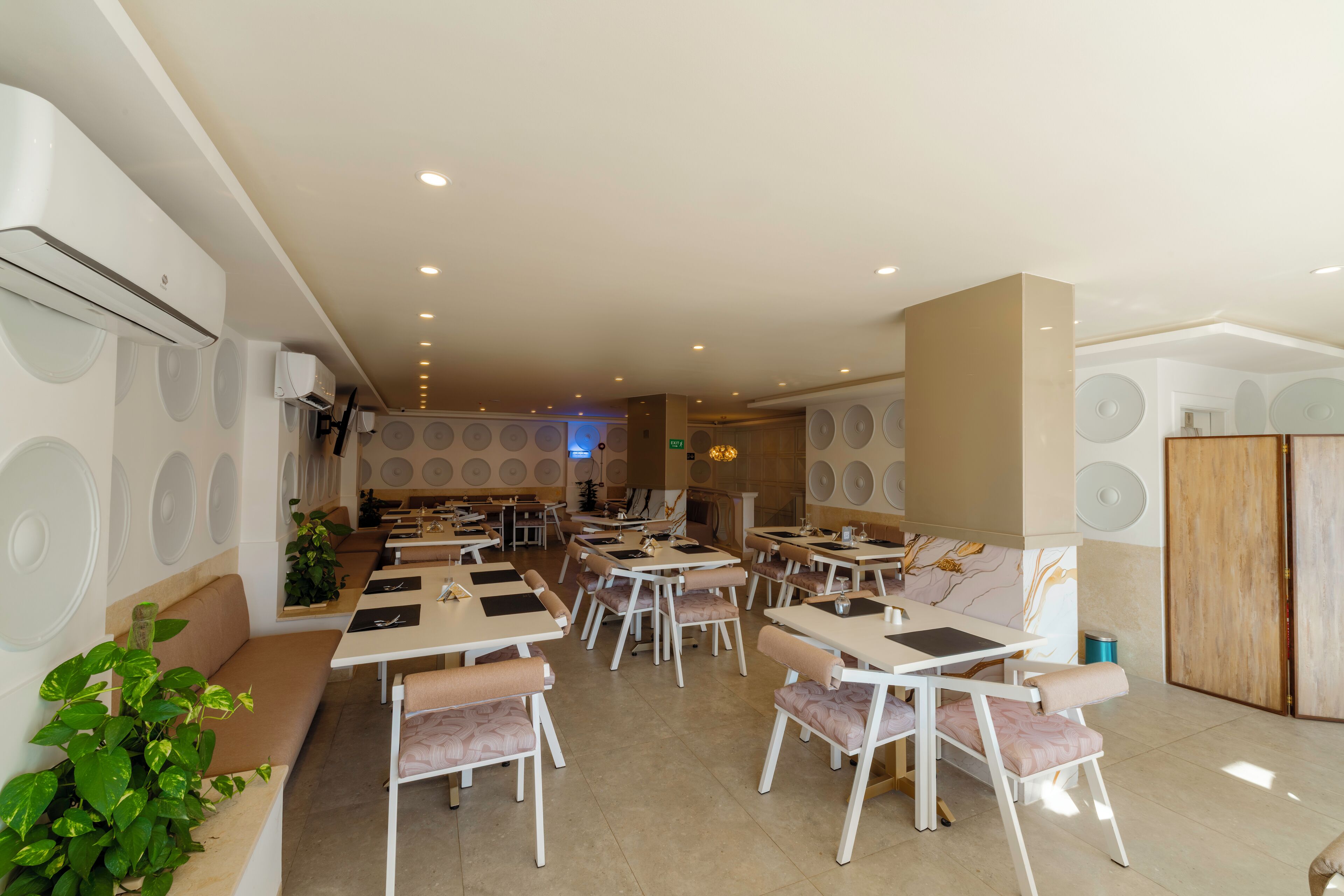 A spacious restaurant with multiple tables and chairs, recessed ceiling lighting, and a modern interior design.