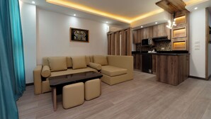 Ein modernes Wohnzimmer mit Ecksofa, Esstisch und Küchenzeile mit Holzausbau und Mikrowelle.