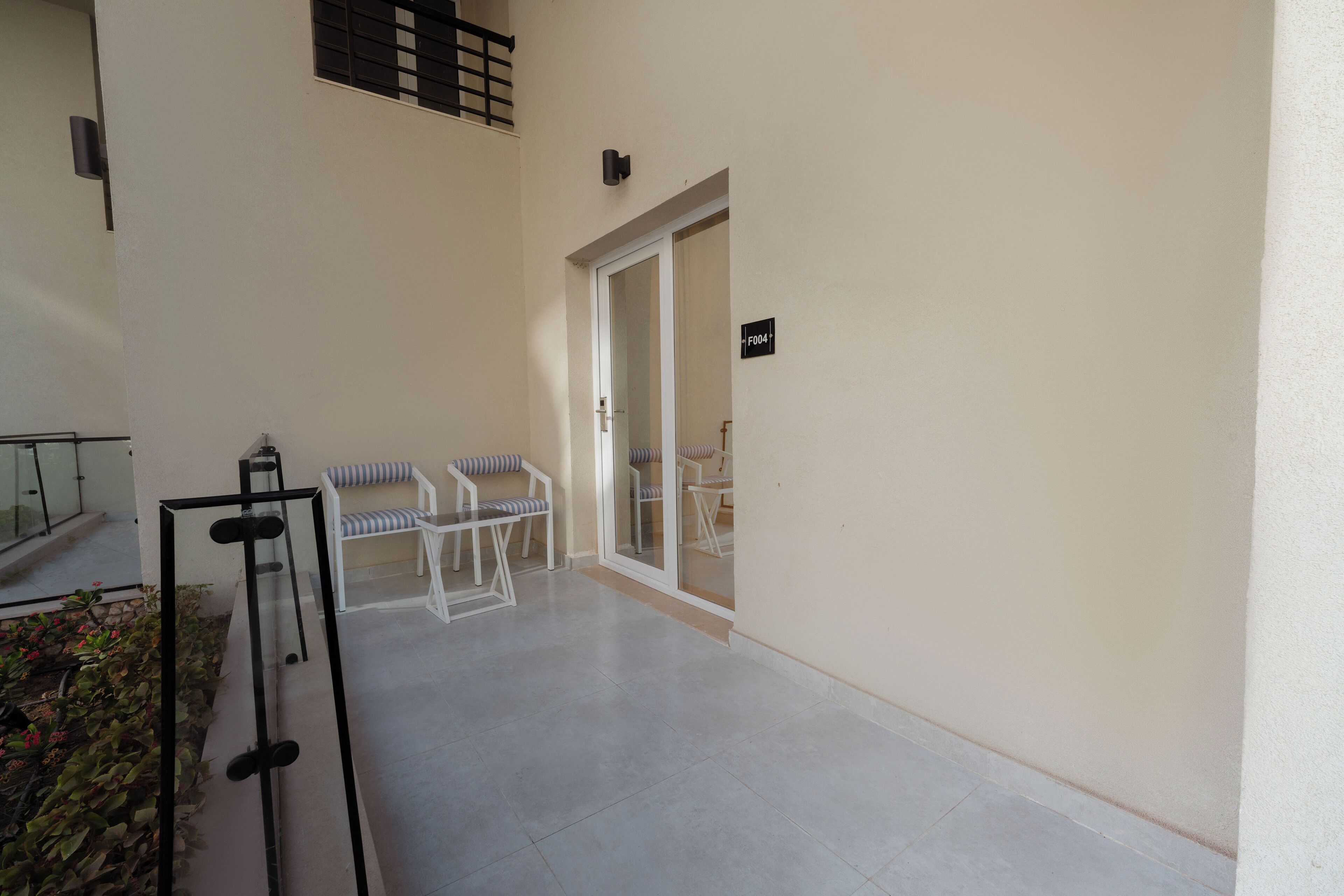 A balcony with a seating area, a door, and a sign indicating room number F004.