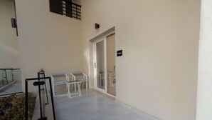 Ein Balkon mit Sitzgelegenheit, einer Tür und einem Schild mit der Zimmernummer F004.