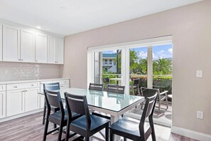 A modern kitchen with white cabinets, a glass dining table, and chairs. - Relaxing Unit K2 · Sanibel Arms West | Easy 2 Minute Walk to the Beach (Sanibel)