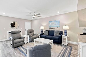 A modern living room with a grey armchair, a blue sofa, a white coffee table, and a ceiling fan. - Relaxing Unit K2 · Sanibel Arms West | Easy 2 Minute Walk to the Beach (Sanibel)