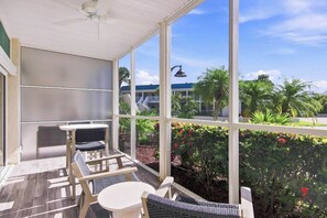 A covered outdoor seating area with a view of a landscaped garden and a building in the background. - Relaxing Unit K2 · Sanibel Arms West | Easy 2 Minute Walk to the Beach (Sanibel)