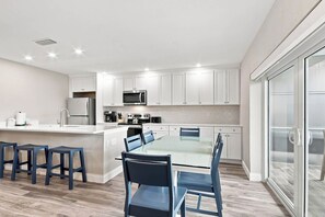 A modern kitchen with white cabinets, stainless steel appliances, and a central island with bar stools. - Relaxing Unit K2 · Sanibel Arms West | Easy 2 Minute Walk to the Beach (Sanibel)