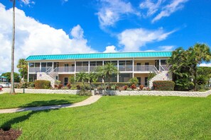 A two-story hotel with a turquoise roof, a covered balcony, and a stone facade. - Relaxing Unit K2 · Sanibel Arms West | Easy 2 Minute Walk to the Beach (Sanibel)