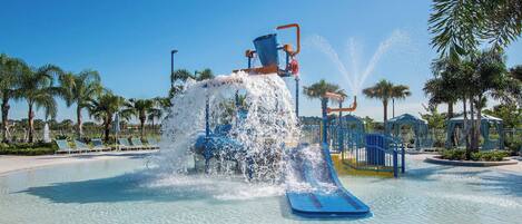 A water park with a water slide, palm trees, and a clear blue sky.