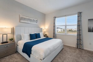 A bedroom with a bed, bedside tables, a window with curtains, and a painting on the wall. - The Splash Shot - Two Bedroom Apartment, Sleeps 6 (Kissimmee)